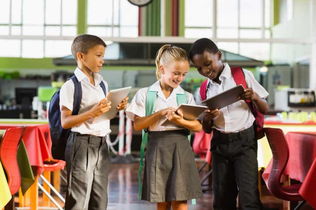 School kids using their tablets while in the cafeteria