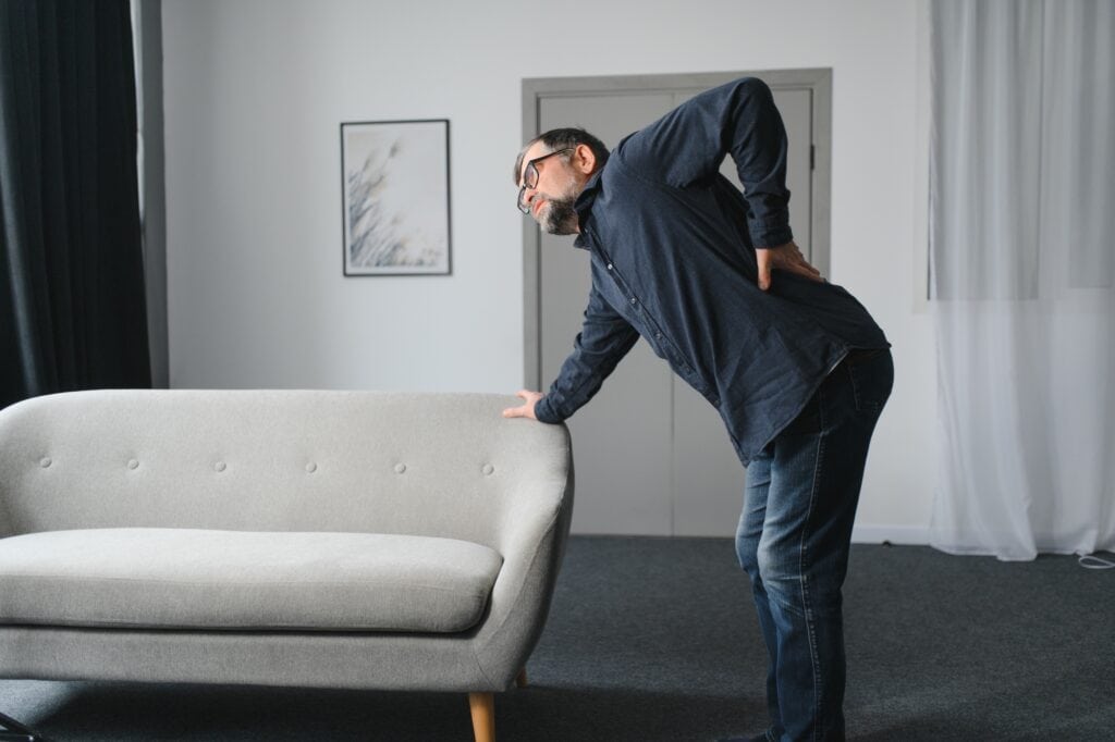 A man holding his back after lifting a sofa